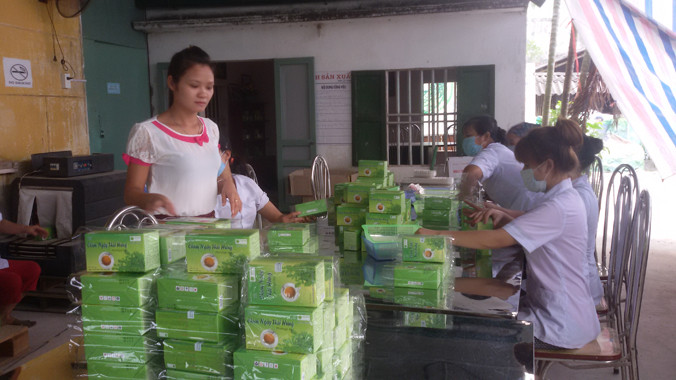 Lê Thị Tỉnh (đứng) bên các sản phẩm trà sản xuất từ những cây dược liệu.