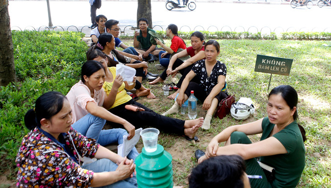 Con cái vào đại học là khát vọng cháy bỏng của nhiều ông bố, bà mẹ ở Việt Nam. Trong ảnh: Cảnh phụ huynh lo lắng ngồi chờ con thi THPT Quốc gia trước cổng trường Đại học Thủy lợi chiều ngày 3/7/2015. Ảnh: Ngọc Châu.