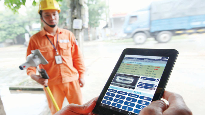 Ghi số công tơ để tính tiền điện bằng phương tiện điện tử. Ảnh: Hồng Vĩnh.