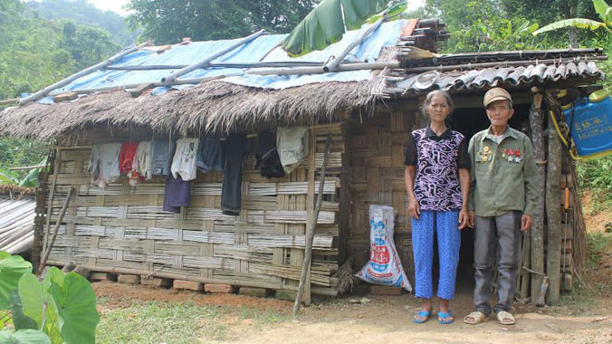 Vợ chồng ông Phín trước túp lều đã xuống cấp. Ảnh: HH.