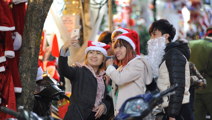 Giới trẻ Hà Nội thích thú với quà tặng Noel trên phố Hàng Mã, Hà Nội. Ảnh: Xuân Tùng.