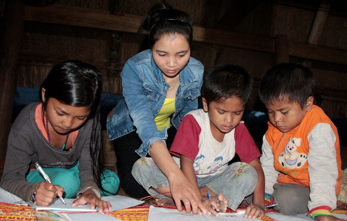 Lớp học dưới mái gươl ở xã Lăng, huyện Tây Giang, tỉnh Quảng Nam. “Cô giáo” là người địa phương, tranh thủ kỳ nghỉ hè dạy các em học bài. Ảnh: Thanh Trần.