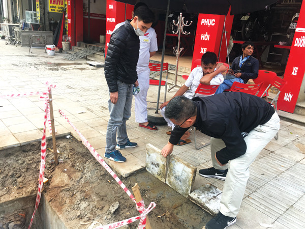 Đá lát trên vỉa hè tuyến phố Đền Lừ (Hoàng Mai) bị lật lên khá dễ dàng dưới sự chứng kiến của người dân. Ảnh: Trường Phong.