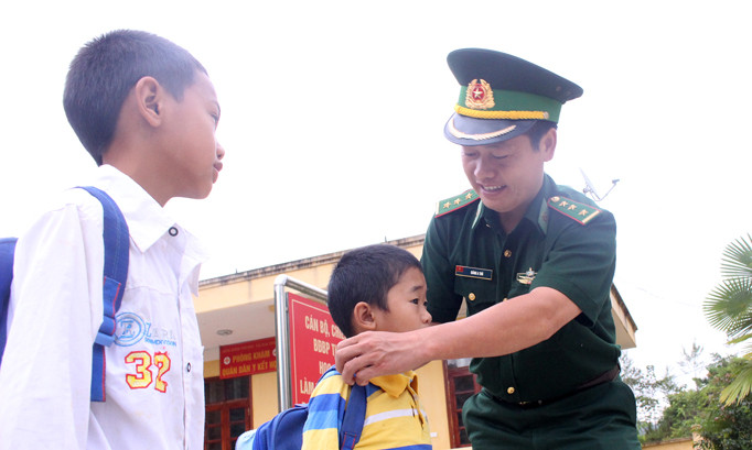 Thượng uý Giàng A Trú vừa là cậu, chỉnh lại trang phục cho anh em Khoa trước khi đến trường. Ảnh: Xuân Tùng.