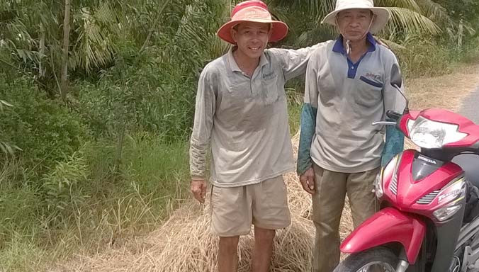 Ông Nguyễn Văn Nam (bìa phải) ở xã Mỹ Hòa và ông Phạm văn Hở ở xã Mỹ Nhơn đang mót rơm phơi trên đường. Ảnh: Thanh Phong.