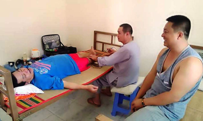 Anh Hùng (bìa phải) xem lương y chữa bệnh cho người dân.