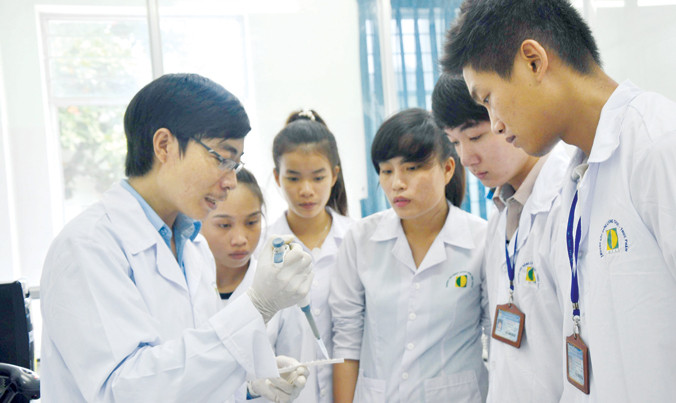 Lê Văn Tình (bìa trái) hướng dẫn sinh viên tại phòng thí nghiệm. Ảnh: Trường An.