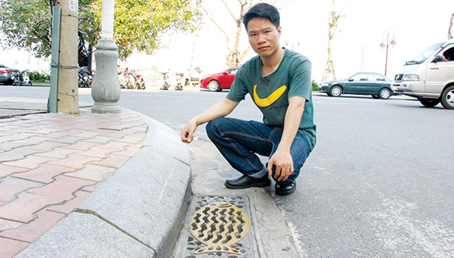 Anh Lê Công Phúc bên cạnh nắp cống hình con cá với chất liệu composite dọc tuyến phố Bạch Đằng xuất phát từ ý tưởng của anh. Ảnh: Đào Phan.