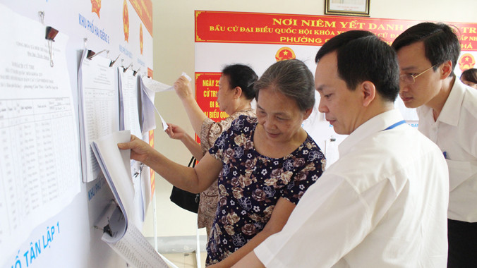 Cán bộ phường hướng dẫn cử tri xem danh sách các đại biểu ứng cử ĐBQH và đại biểu HĐND các cấp nhiệm kỳ 2016 - 2020. Ảnh: QNP.