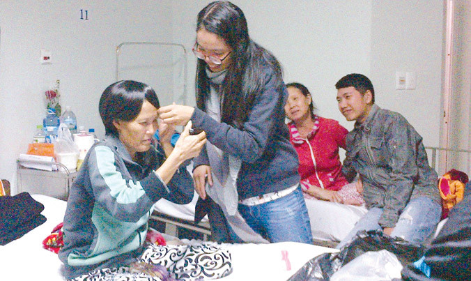 Một thành viên của nhóm “Một bức tranh - Nhiều hy vọng” sửa sang đầu tóc giả cho nữ bệnh nhân.