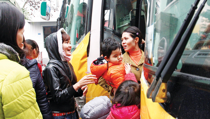 Nhiều nữ công nhân và con nhỏ hồ hởi về quê đón Tết trên những chuyến xe miễn phí. Ảnh: Xuân Tùng.