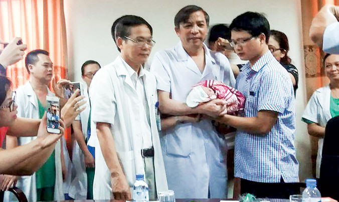 PGS.TS Vũ Bá Quyết, Giám đốc BV Phụ sản T.Ư trao bé Gấu cho người cha.