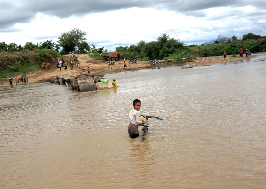 Em nhỏ dắt xe đạp vượt sông