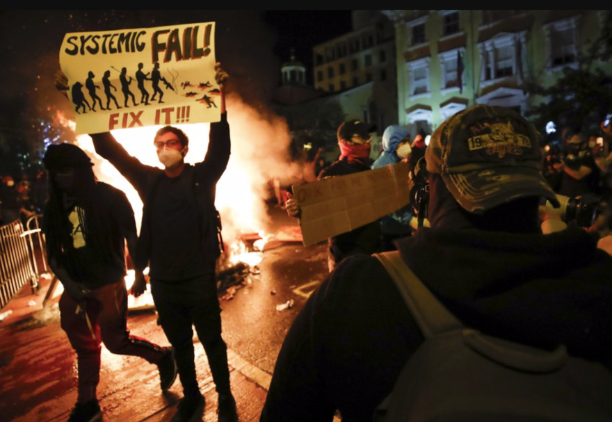  Một người biểu tình Mỹ giương tấm biển có khẩu hiệu “Systemic Fail” (Thất bại hệ thống) gần Nhà Trắng ngày 31/5 ảnh: AP 