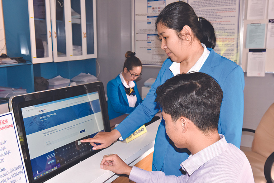 Nhân viên Công ty Điện lực Bình Thuận hướng dẫn khách hàng thao tác thanh toán tiền điện trực tuyến Ảnh: Văn Hơn 