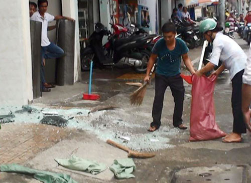 Người của tòa nhà thu dọn mảnh kính vỡ vụn dưới đường. Ảnh: An Nhơn
