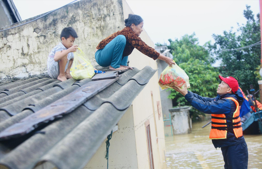 Bà Biên Thị An nhoài người nhận hàng cứu trợ 