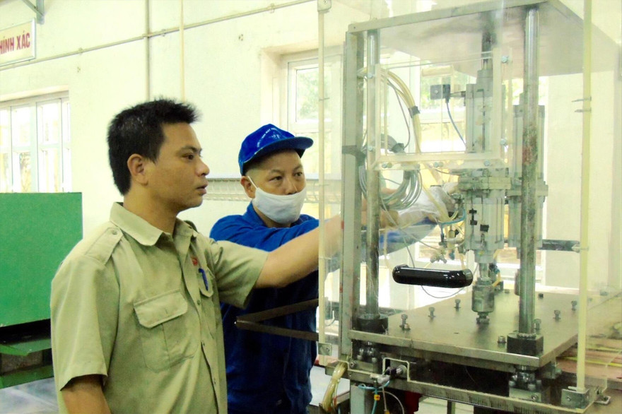 Kỹ sư Nguyễn Tiến Hưng (trái) kiểm tra thiết bị sản xuất sản phẩm quốc phòng tại Xí nghiệp II . Ảnh: PV