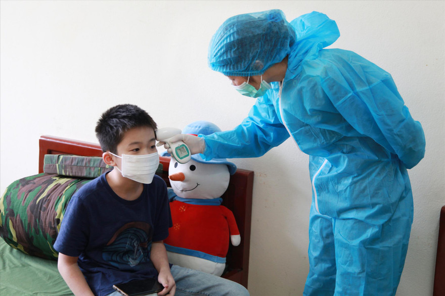 Quân y Bùi Thị Thắm kiểm tra thân nhiệt cho một cháu nhỏ trong khu cách ly ẢNH: PV 