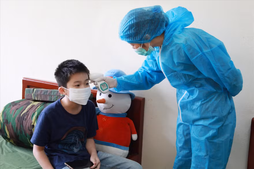 Quân y Bùi Thị Thắm kiểm tra thân nhiệt cho một cháu nhỏ trong khu cách ly ẢNH: PV 