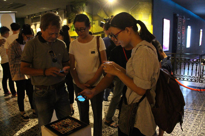 Người xem triển lãm trải nghiệm công nghệ 3D AR Art và thích thú khi hình ảnh cầu Rồng, cầu sông Hàn... hiện lên chân thực từ mọi góc độ. Ảnh: Giang Thanh.