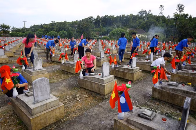 Thí sinh Hoa hậu Việt Nam 2018 cùng đoàn viên, thanh niên huyện Anh Sơn thắp hương, nến tại Nghĩa trang Việt – Lào. Ảnh: Như Ý.