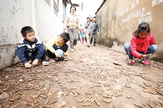 Trẻ em vẫn vô tư nhặt đạn được rải như vãi thóc trên đường làng Quan Độ (xã Văn Môn, huyện Yên Phong, Bắc Ninh) sau vụ nổ. Ảnh: Phạm Tuấn.