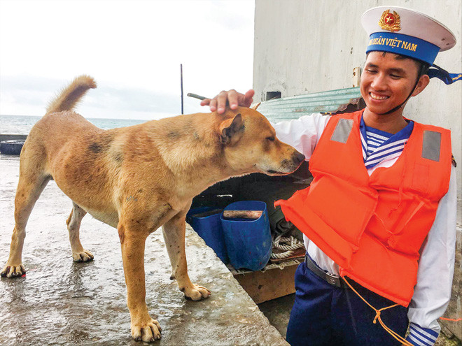 Chiến sĩ Não Xuân Long chia tay chú chó Bin bên cầu cảng đảo Tiên Nữ Ảnh: Trường Phong.