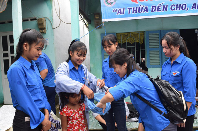 Các bạn tình nguyện viên mặc đồ cho trẻ em. Ảnh: H.H.