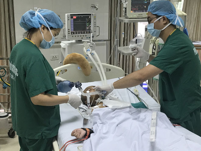 Ðiều dưỡng Thảo và Giang đang hút dịch cho bệnh nhi hôn mê. Ảnh: Ảnh T.Hà.
