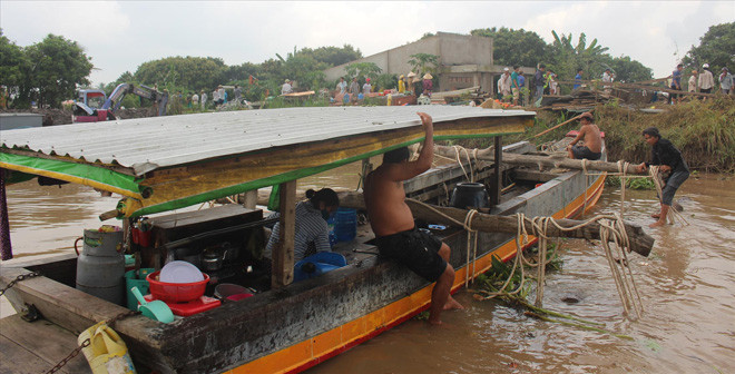 Người dân trục vớt nhà bị sụp xuống sông. Ảnh: Hoà Hội.