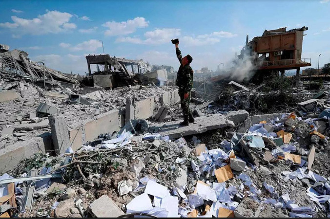 Một người lính Syria khảo sát đống đổ nát của một cơ sở nghiên cứu khoa học sau khi Mỹ, Anh và Pháp không kích hôm 14/4. Ảnh: AP