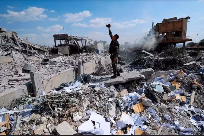 Một người lính Syria khảo sát đống đổ nát của một cơ sở nghiên cứu khoa học sau khi Mỹ, Anh và Pháp không kích hôm 14/4. Ảnh: AP