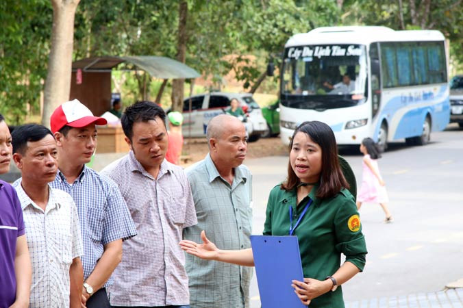 Chị Lương Thị Thủy đang thuyết minh về di tích hố bom cho đoàn khách tham quan.Ảnh: V.B.