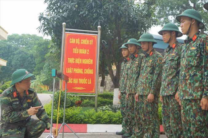 Thiếu tá Nguyễn Văn Thanh (trái) hướng dẫn đồng đội sử dụng thước bắc cầu TMM-3M đa năng dùng pin sạc do anh sáng chế, nhằm rút ngắn thời gian thao tác bắc dỡ cầu, nhất là vào ban đêm. Ảnh: NGUYỄN MINH.