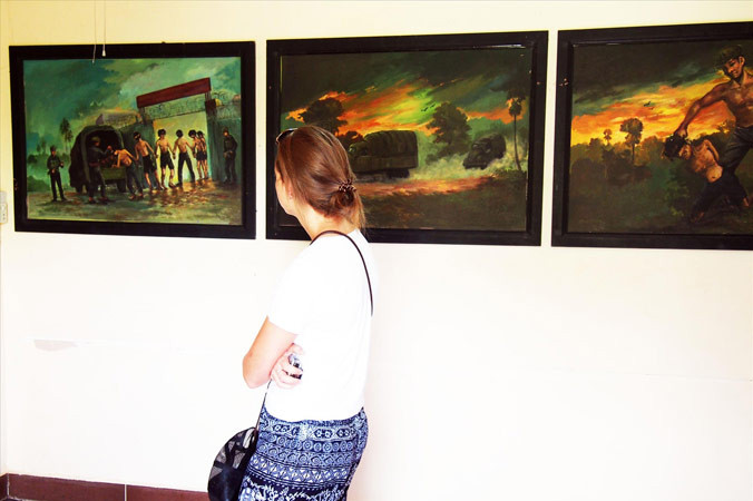 Du khách xem những bức tranh tái hiện cảnh tra tấn tại “Cánh đồng chết”.