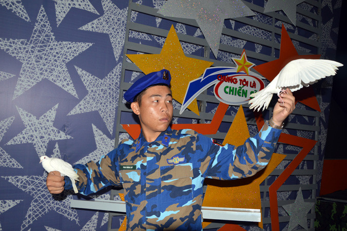 Binh nhì - ảo thuật gia Phạm Đình Quý động viên những chú chim của mình trước giờ biểu diễn. Ảnh: L.G.