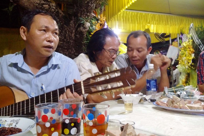 Tác giả Bùi Long ôm đàn trong đám tang thi sĩ Trần Vàng Sao. Ảnh: Trần Tuấn.
