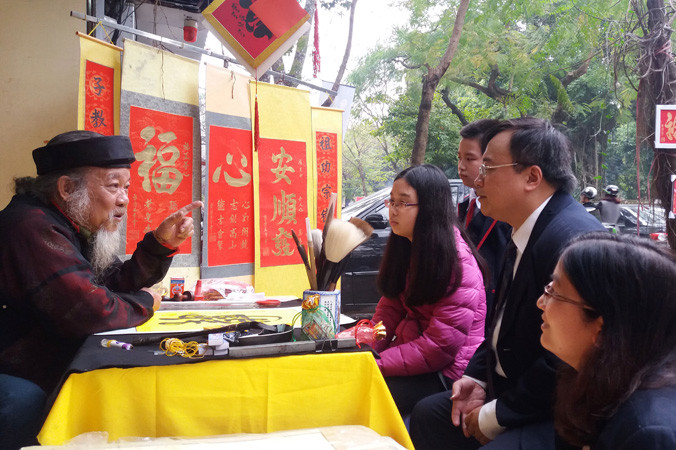 Ông đồ Vũ Ngọc Kỳ giải thích về ý nghĩa của chữ trước khi viết cho khách du xuân. 