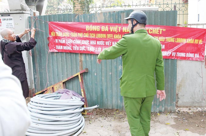Cựu trọng tài bóng đá Dương Mạnh Hùng tháo gỡ băng-rôn theo yêu cầu của cơ quan chức năng. Ảnh: Thành Duy.