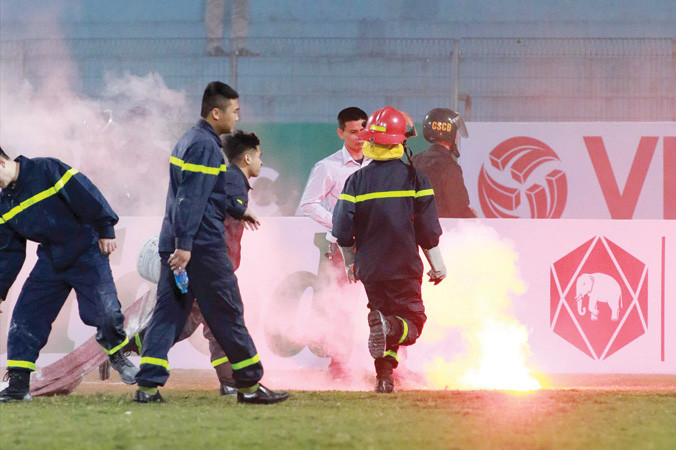 Lực lượng cứu hỏa cố gắng dập tắt những quả pháo sáng được CĐV Hải Phòng ném xuống sân Hàng Đẫy ở lượt trận đầu tiên. Ảnh: VSI.