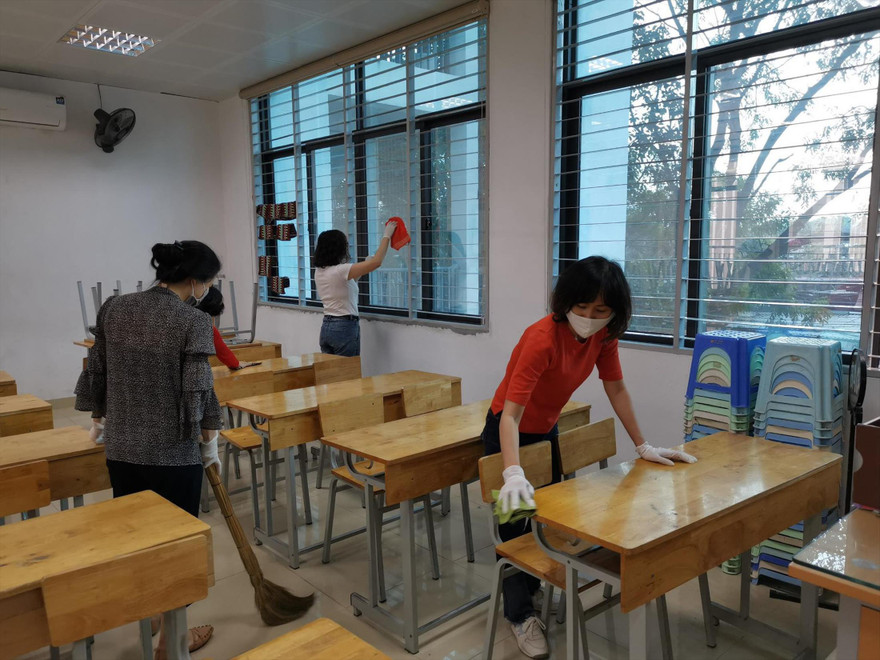 Giáo viên Trường THCS Kim Giang (Hà Nội) lau bàn ghế học sinh bằng dung dịch khử khuẩn chiều 26/2 
