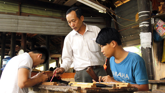 Ông Nguyễn Văn Tiếp hướng dẫn chạm khắc cho thanh niên mới học nghề. Ảnh: Thanh Trần