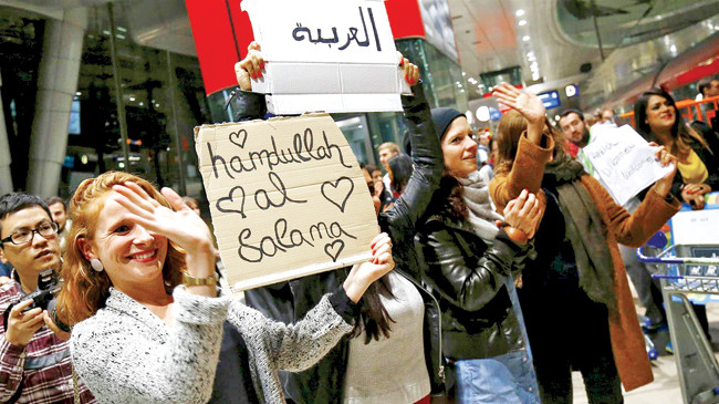 Một phụ nữ Đức giơ tấm biển tự làm với dòng chữ chào mừng người di cư. Ảnh: NBC News