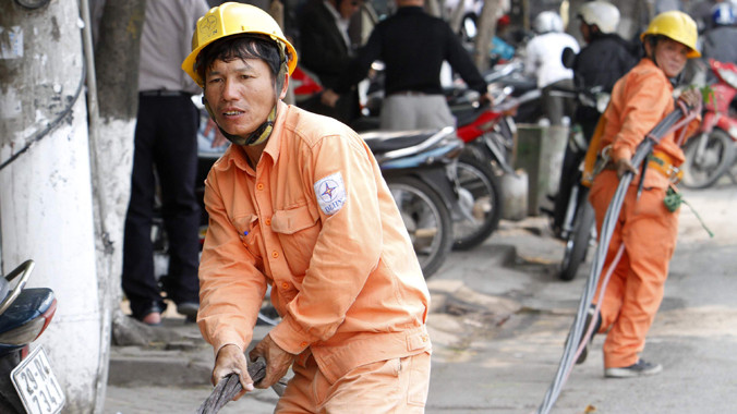 Giá điện tăng dưới 7%, EVN sẽ được tự tăng giá (công nhân điện lực đang kéo đường dây điện trên đường Giải Phóng - Hà Nội). Ảnh: Ngọc Châu