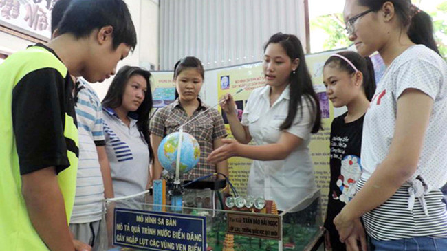 Trần Đào Hải Ngọc (áo trắng) với mô hình sa bàn mô tả quá trình nước biển dâng gây ngập lụt các vùng ven biển. Ảnh: H. Văn