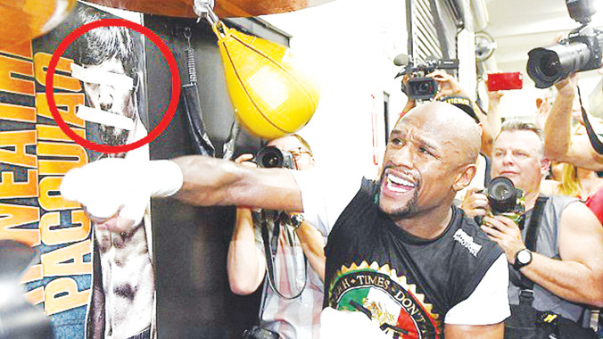 Mayweather tập luyện bên tấm poster có hình đối thủ Pacquiao của anh bị bịt mắt, bịt miệng bằng băng keo. Ảnh: Getty Images