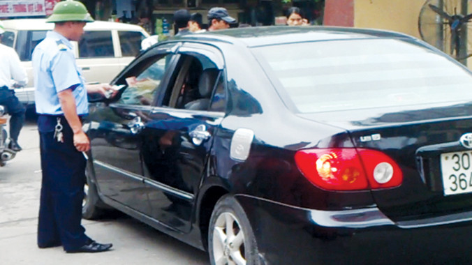 Nhân viên bảo vệ thu tiền ô tô tư nhân vào đỗ trong Bệnh viện Việt - Đức sáng 27/3. Ảnh: Tuấn Nguyễn