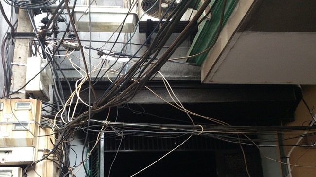 Cột điện chằng chịt dây dợ phía trước cửa nhà nạn nhân