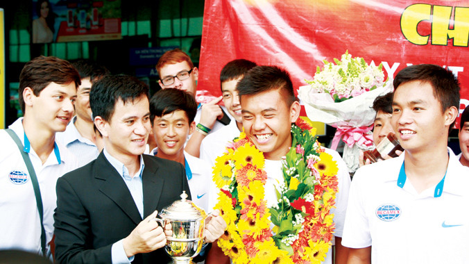 Lý Hoàng Nam (giữa) trong vòng vây người hâm mộ và lãnh đạo Becamex tại sân bay Tân Sơn Nhất. Ảnh: Ngô Tùng